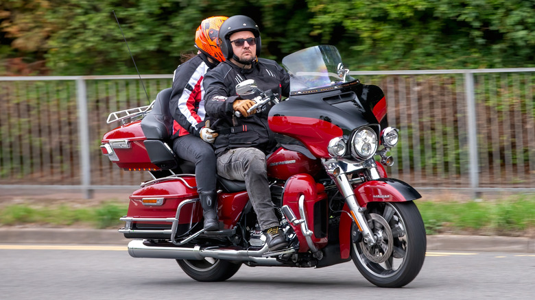 Two people riding a 2021 red Harley Davidson Ultra Limited motorcycle
