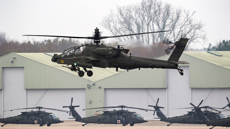 AH-64 Apache landing with Blackhawk helicopters on the background