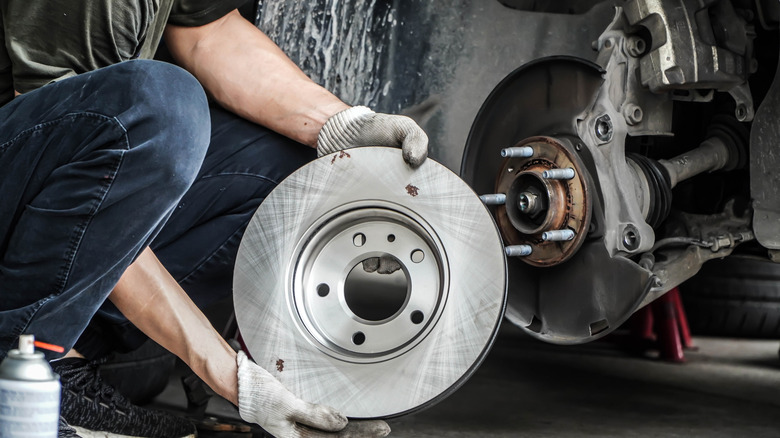 Person holding brake pads and brake rotors