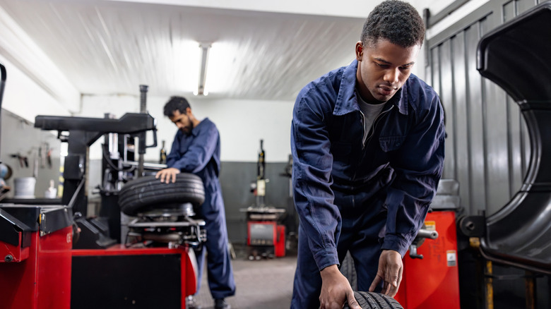Team of mechanics working at an auto repair shop fixing flat tires