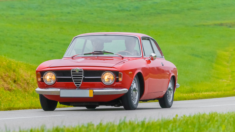 front view of red 1967 Alfa Romeo Giulia GT Junior driving on country road