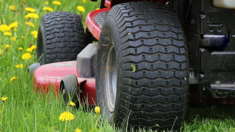 Riding lawn mower tires showing signs of wear from normal use.