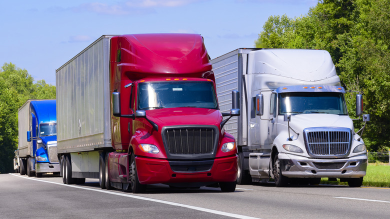 A group of semi trucks driving on the highway