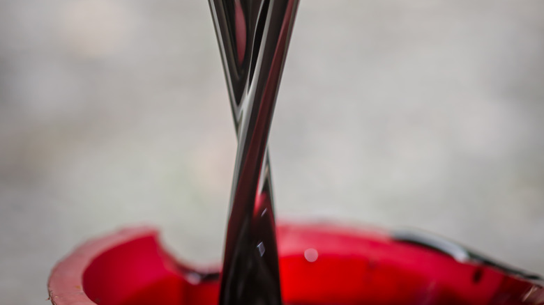 Draining used motor oil into red bucket
