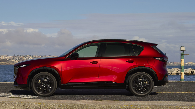 A side view of a red 2026 Mazda CX-5 parked seaside.