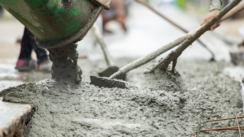 A mixer pouring concrete while workers level the concrete