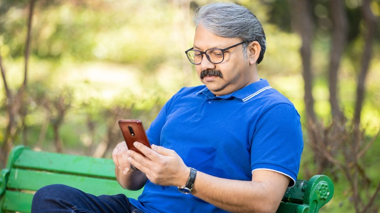person on bench holding smartphone