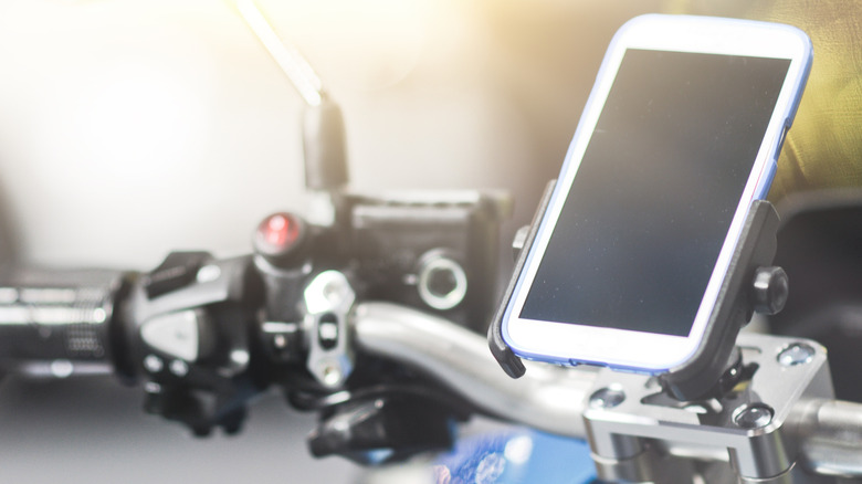 A white cell phone charging on a motorcycle