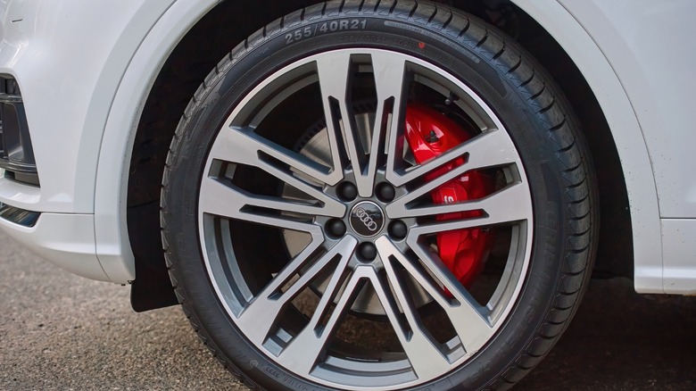 A closeup image of an audi car wheel with red brake calipers visible through the spokes