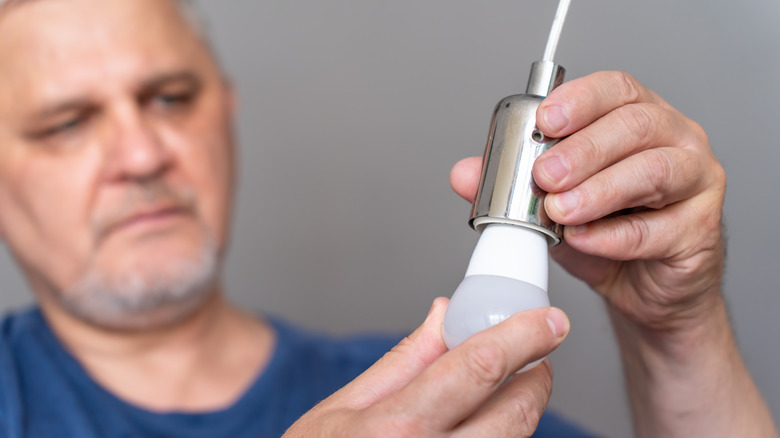 A man inserts a light bulb into a socket.