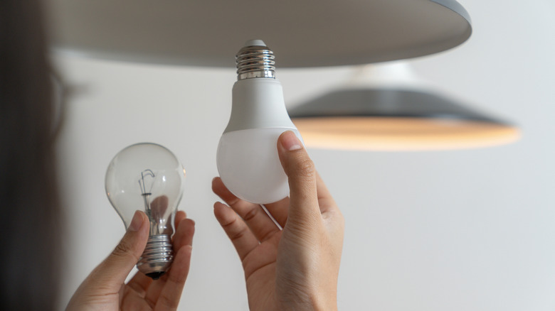 Replacing a glass light bulb with an LED light bulb.