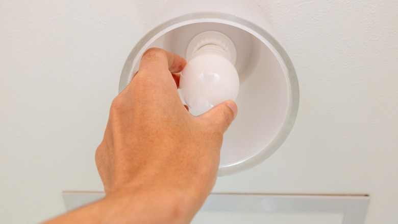 Removing a light bulb in a lighting fixture.