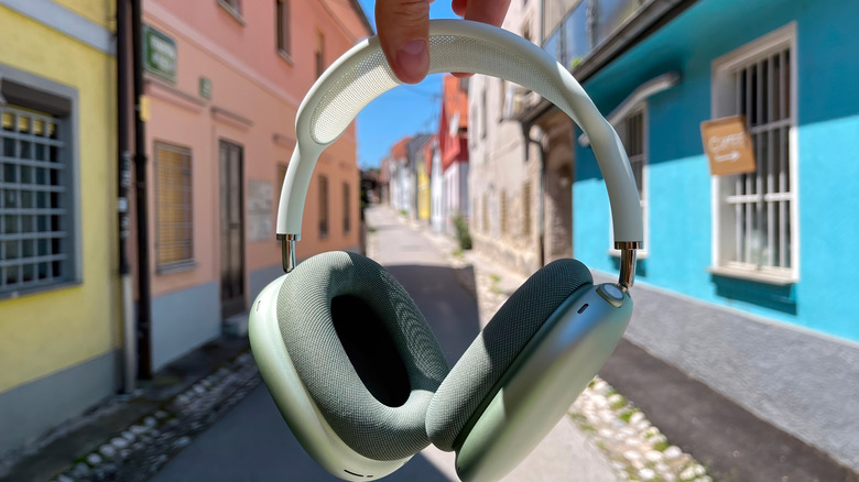 Person holding AirPods Max with a street background