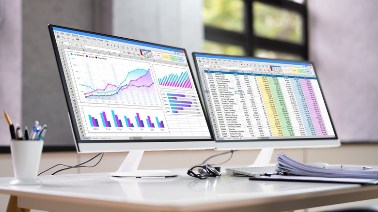 Dual monitor computer setup displaying spreadsheet tables and data points
