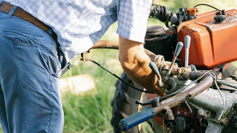 A man draining the gas from a lawn mower.