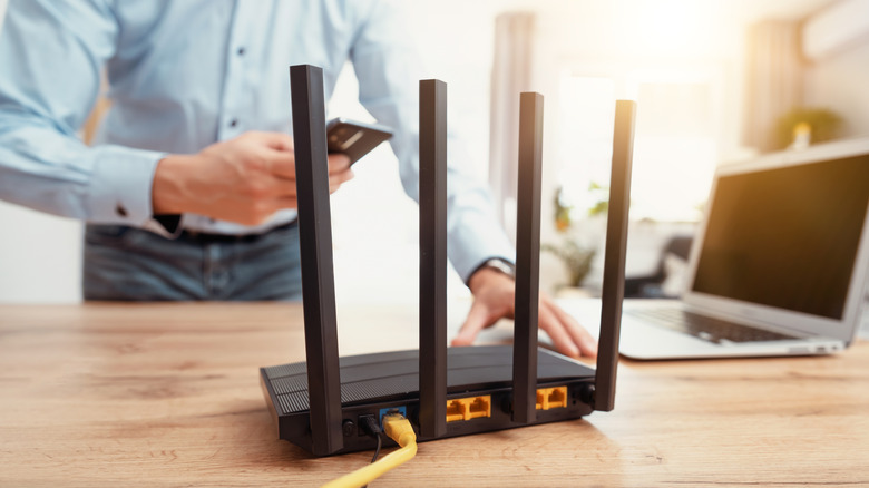 Black router with man holding a phone in the background