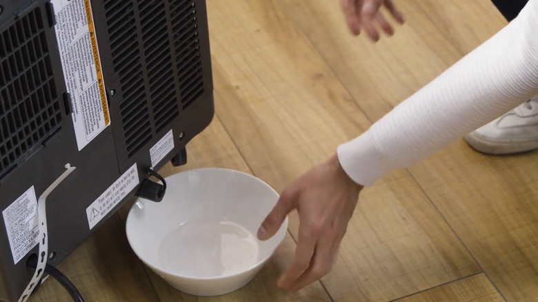 Man drainng water collection tank on Hisense portable airconditioner