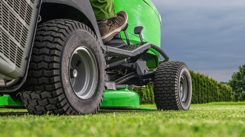 A person cutting grass on a riding lawn mower.