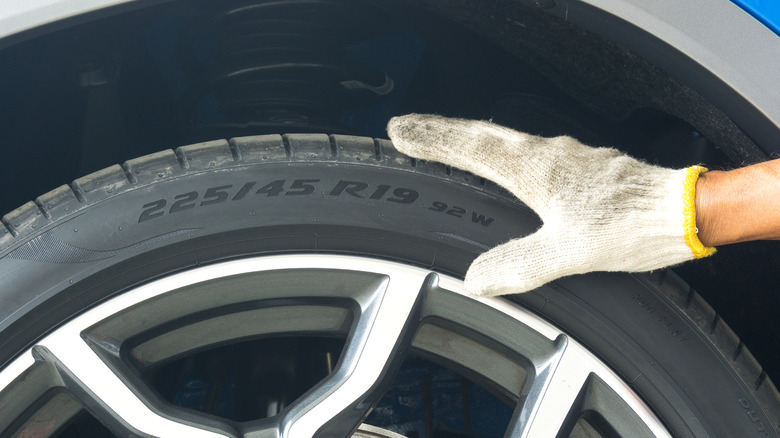 Hand holding tire showing sidewall information with top speed rating