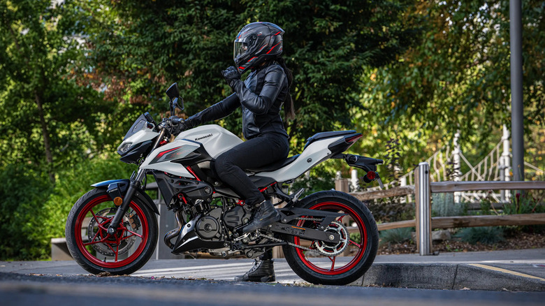 Rider seated on a white Kawasaki Z500 motorcycle with red wheels, side view