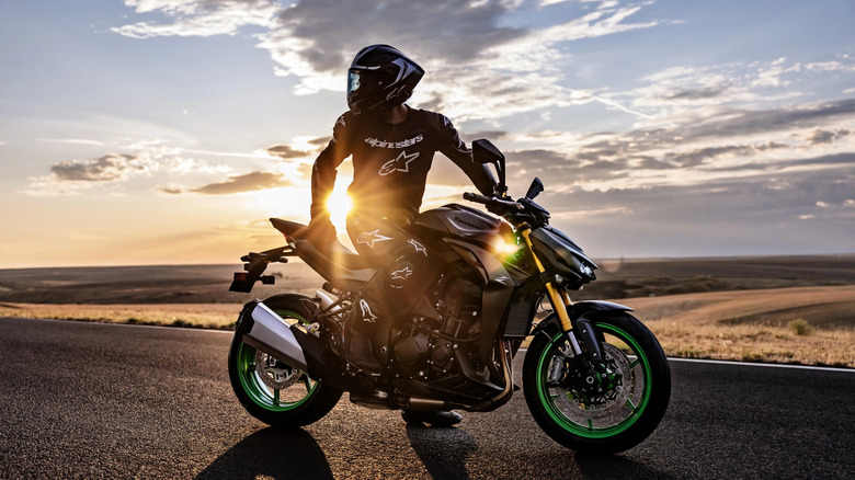 Kawasaki Z1100 with a rider dressed in Alpinestars gear sitting on top, sunset, side view