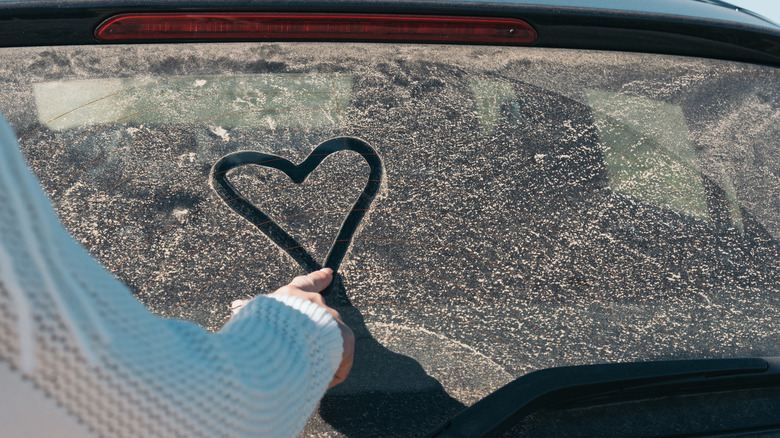 Heart being drawn on a dirty car window