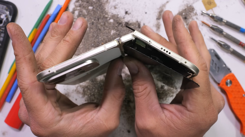 A screenshot of the JerryRigEverything YouTube channel showing hands breaking a phone in half.