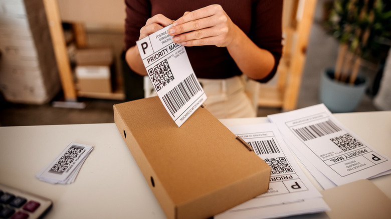 a woman attaching mailing label to a parcel