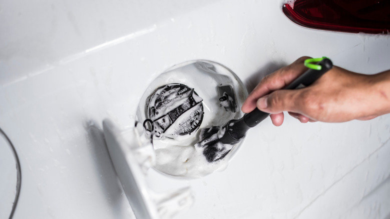 Person cleaning gas compartment on car