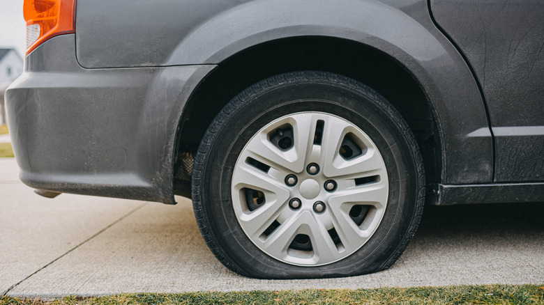 Car parked in a driveway with a flat tire