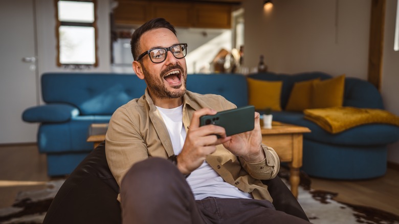 Man playing smartphone on couch