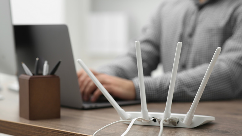 Man typing by router