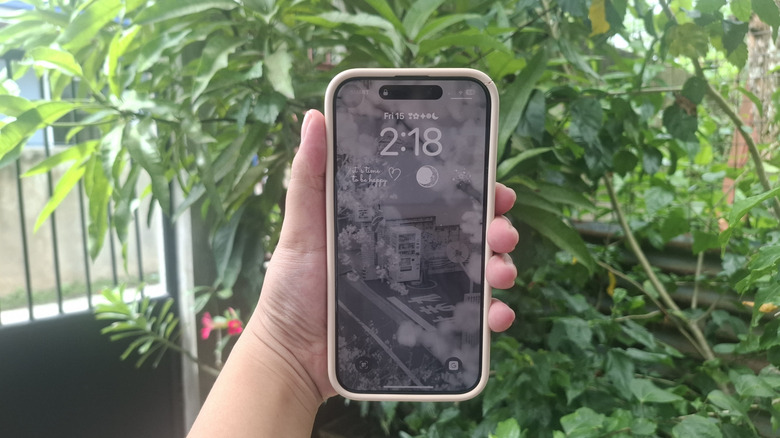 A person holding iPhone showing grayscale lockscreen