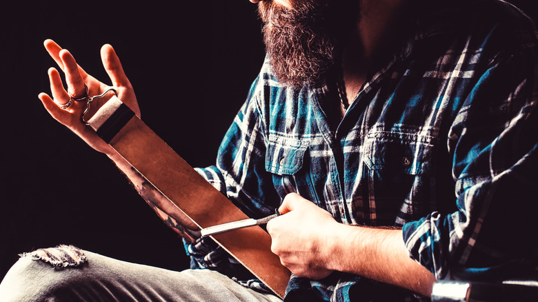 Man sharpening a razor with a leather strop