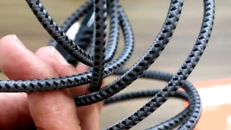 A hand holding a black braided cable