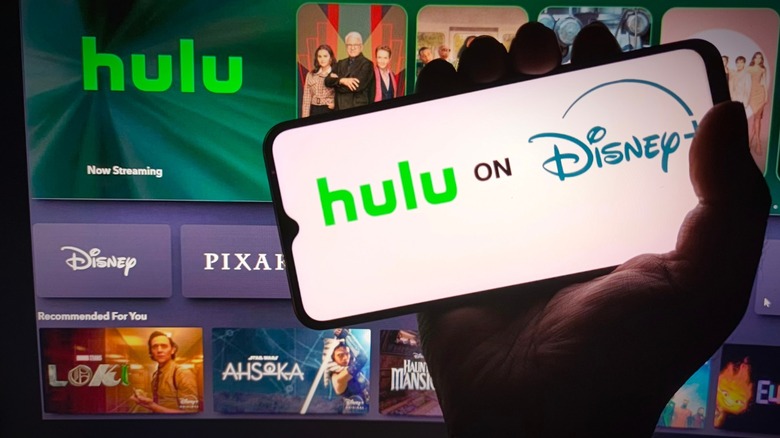 Hulu on Disney Plus displaying on a phone with Hulu app on the TV in the background