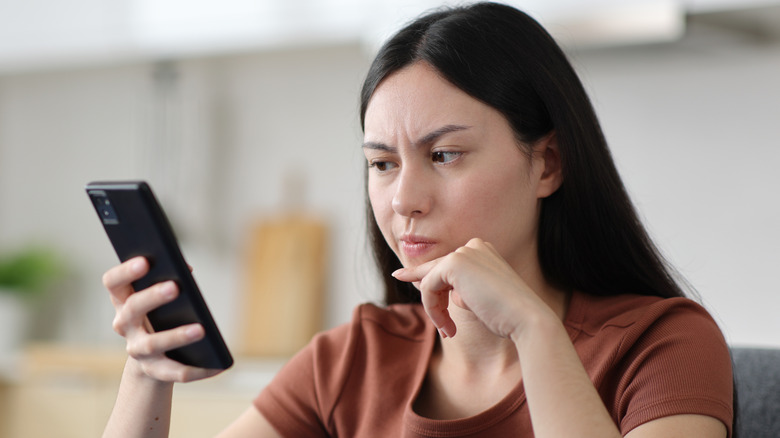 Woman looking sceptically at a phone