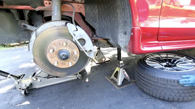 A red Ford Mustang with its wheel removed, revealing the whole brake assembly