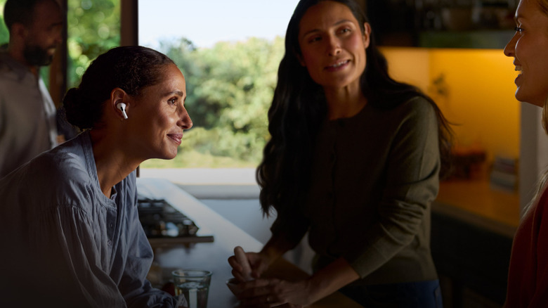 Woman wearing AirPods Pro while having conversation with others