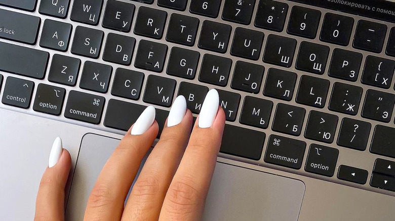 Hands with long nails on a laptop keyboard