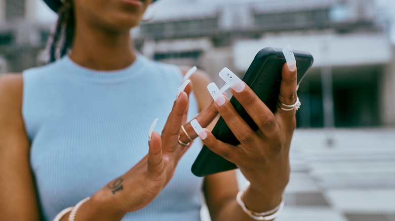 Woman with long nails typing on a phone