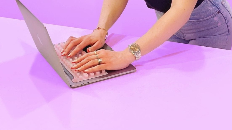 Woman with long nails using tippy type on laptop