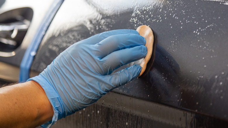 Close up of a detailer using a clay bar on a car