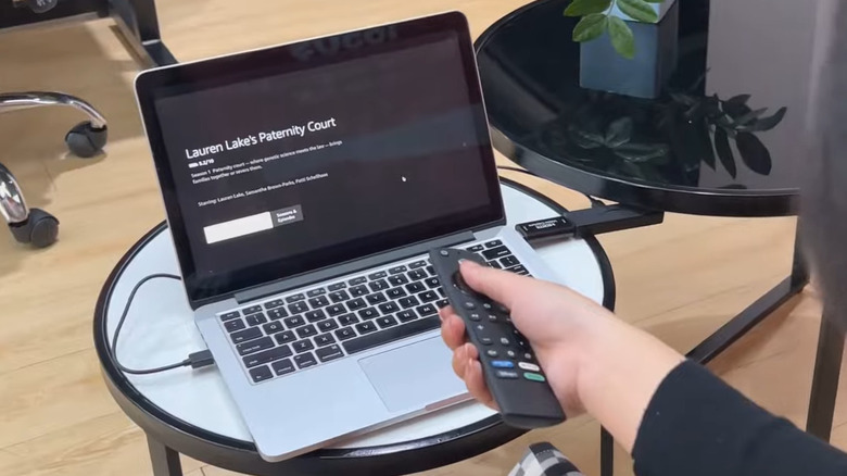 A person controlling Fire TV Stick connected to a laptop using the remote
