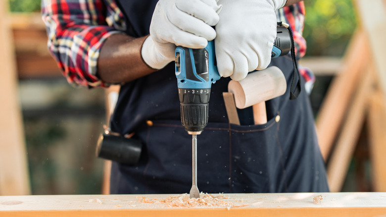 A person using a drill on a piece of wood.