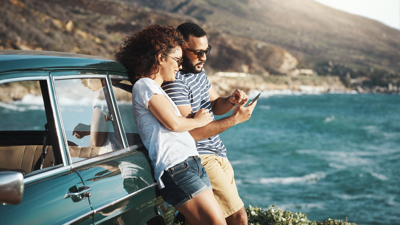 man and woman using smartphone outdoors