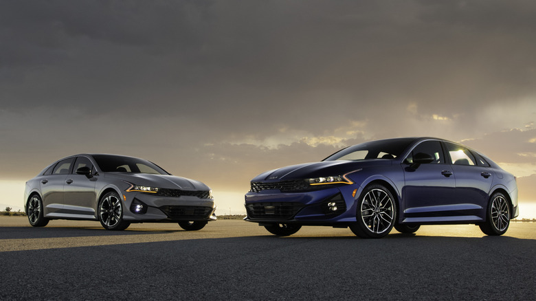 Two 2024 Kia K5 cars parked facing one another, showing front-right and front-left 3/4 views