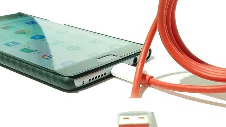 A OnePlus 3 with its red charging cable plugged in
