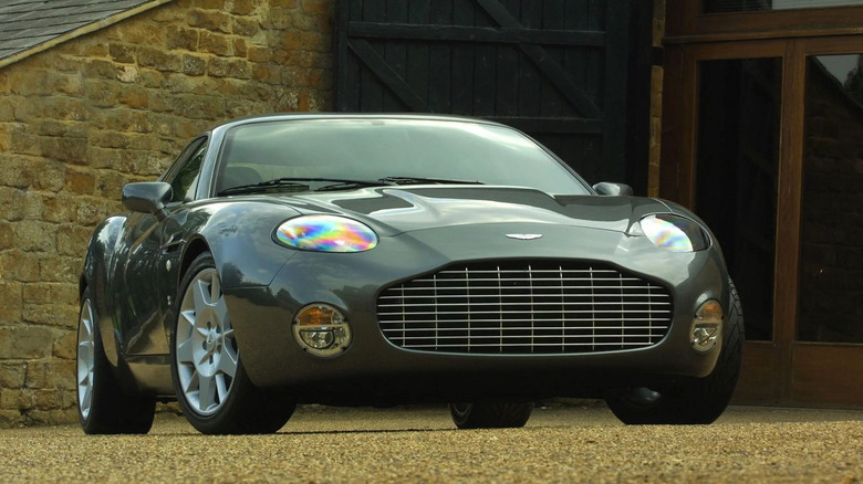 Rare Aston Martin DB7 Zagato in metallic grey parked on a gravel driveway, featuring signature Zagato design with rounded headlights and distinctive front grille.