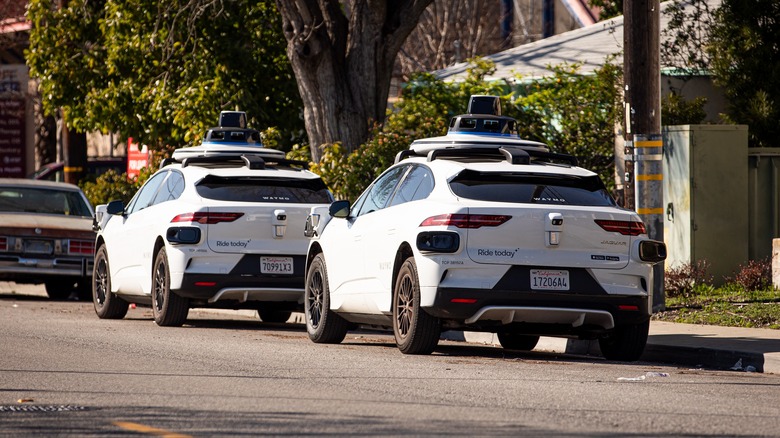 Two Waymo taxis parked on a street